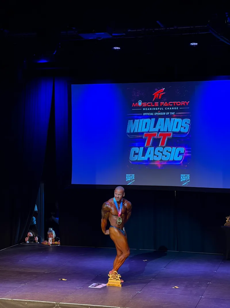 Tom holding a medal from a bodybuilding competition